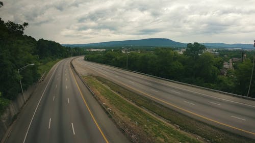 Time Lapse Footage Of Clouds Over An Empty Highway Lined With Trees