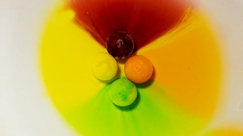 水に溶けるカラフルな砂糖でコーティングされたキャンディーのタイムラプス映像
