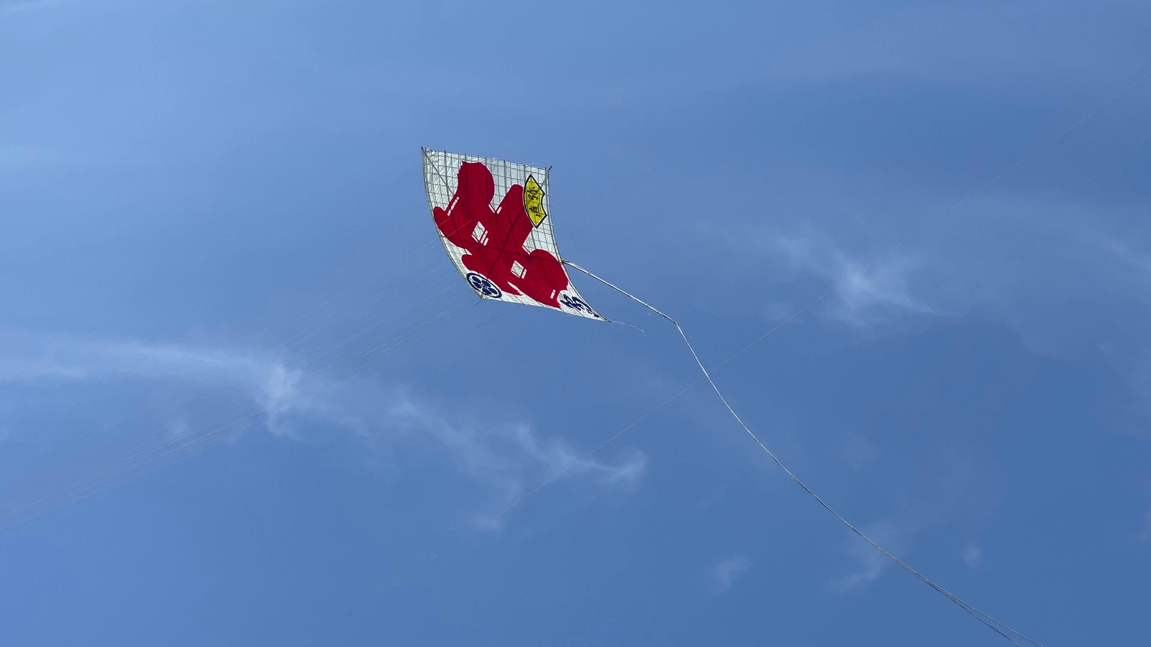 A kite flying in the blue sky with a red and white star Free Stock
