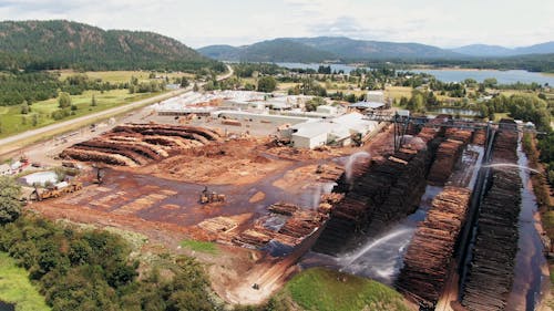 Luftaufnahme, Luftaufnahme, Drohnenaufnahmen, Holzplatz, Hof, Geschäft, Holz, Holz, Holz, Wasser, Sprinkler, Wassersprinkler, Schwere Maschinen, Arbeiter, Werksgelände