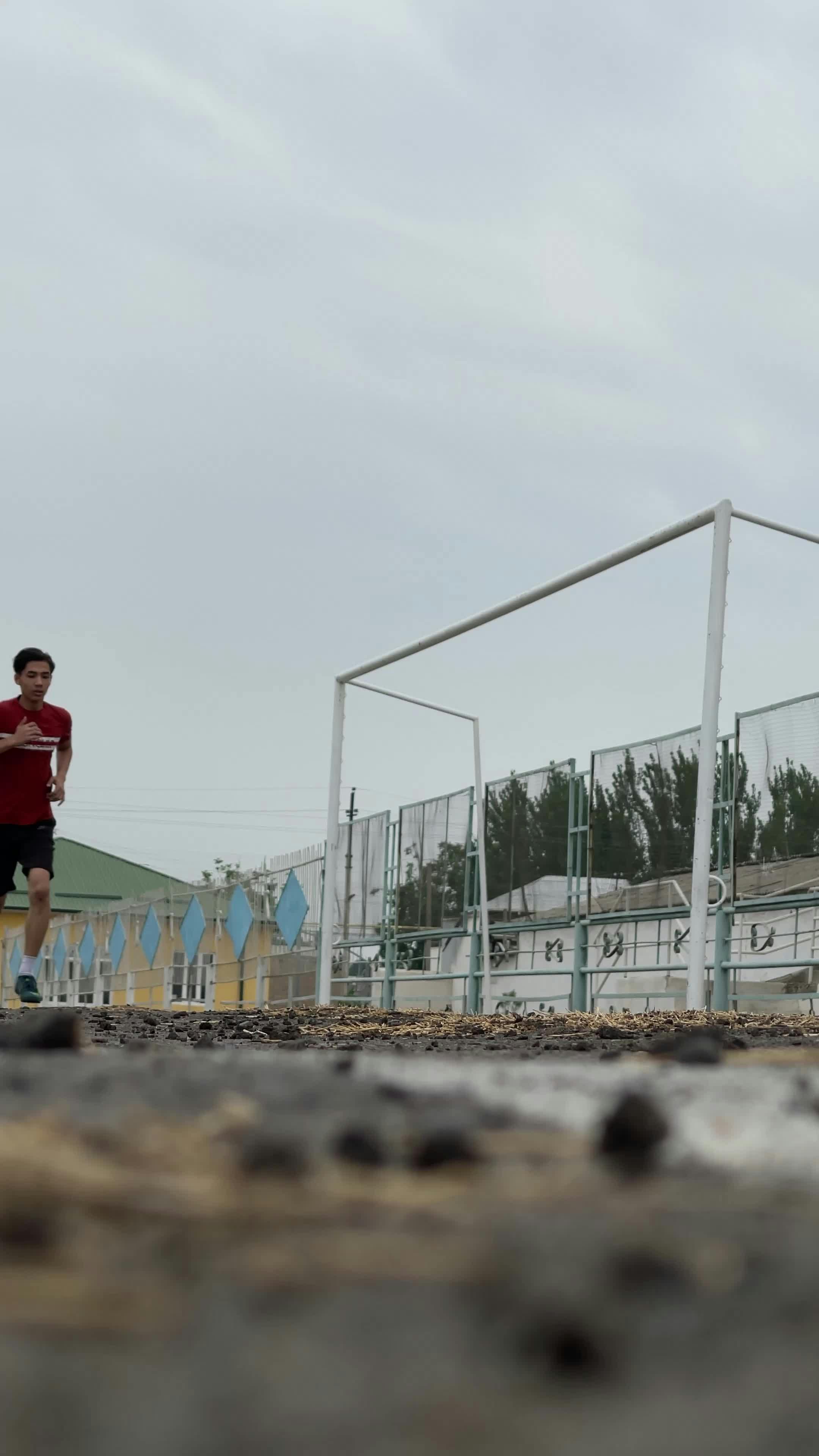 a man running on a track with a fence in the background 27385423