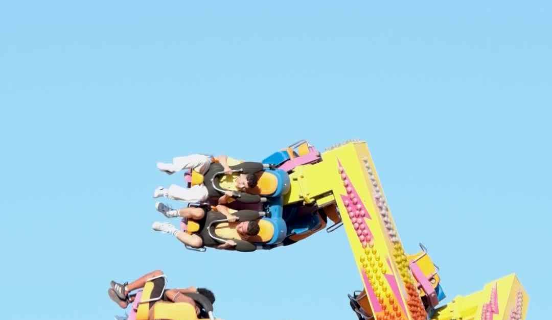 Exhilarating Rides Exhilarating Carnival Ride with Colorful Arms Against Clear Blue Sky ...