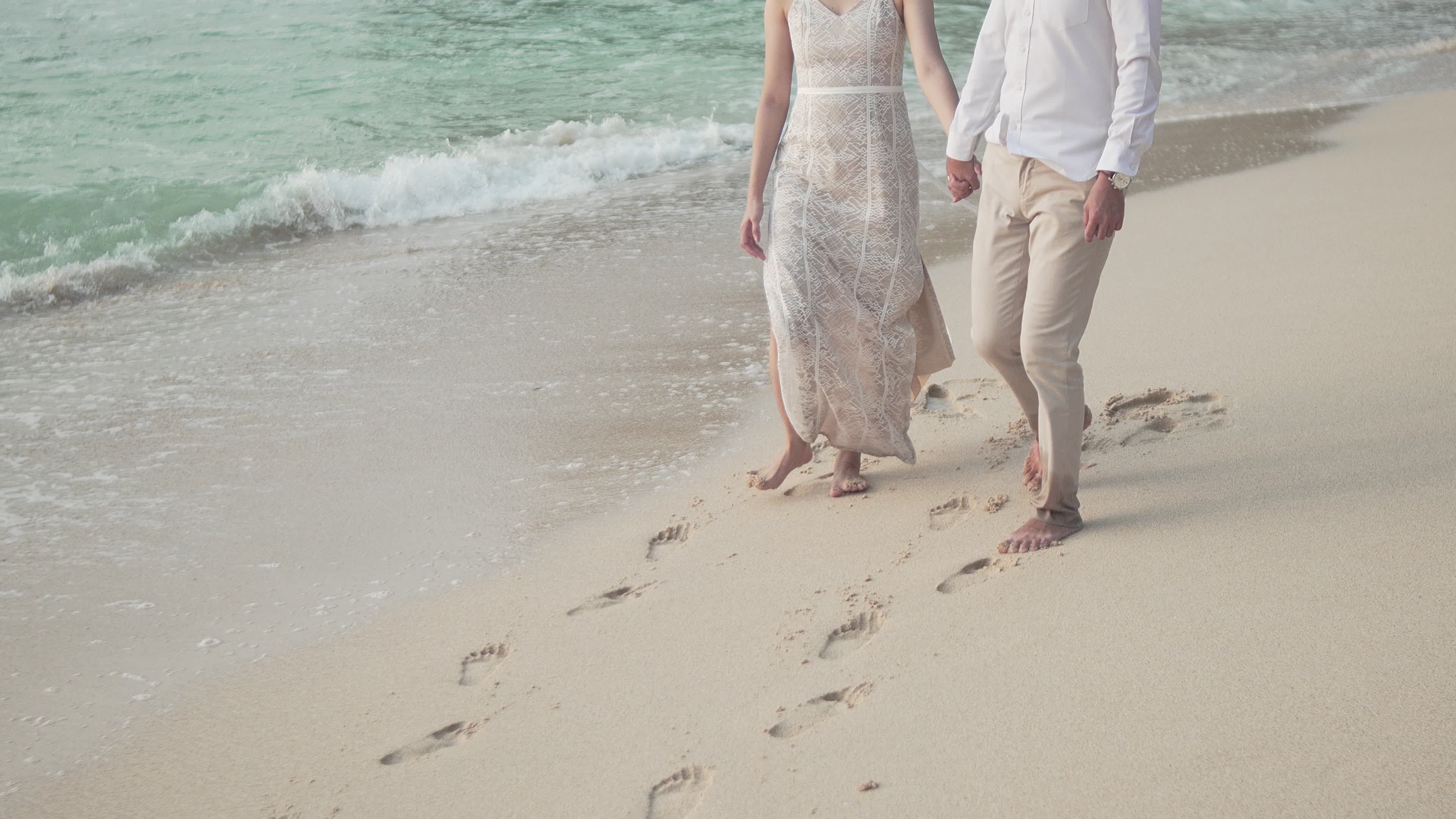 A couple walking on the beach with footprints in the sand Free Stock ...