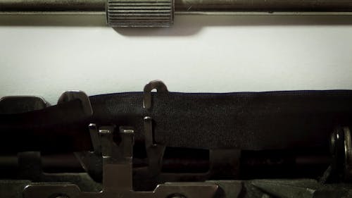 Человек, печатающий на высокосортной бумаге с винтажной пишущей машинкой