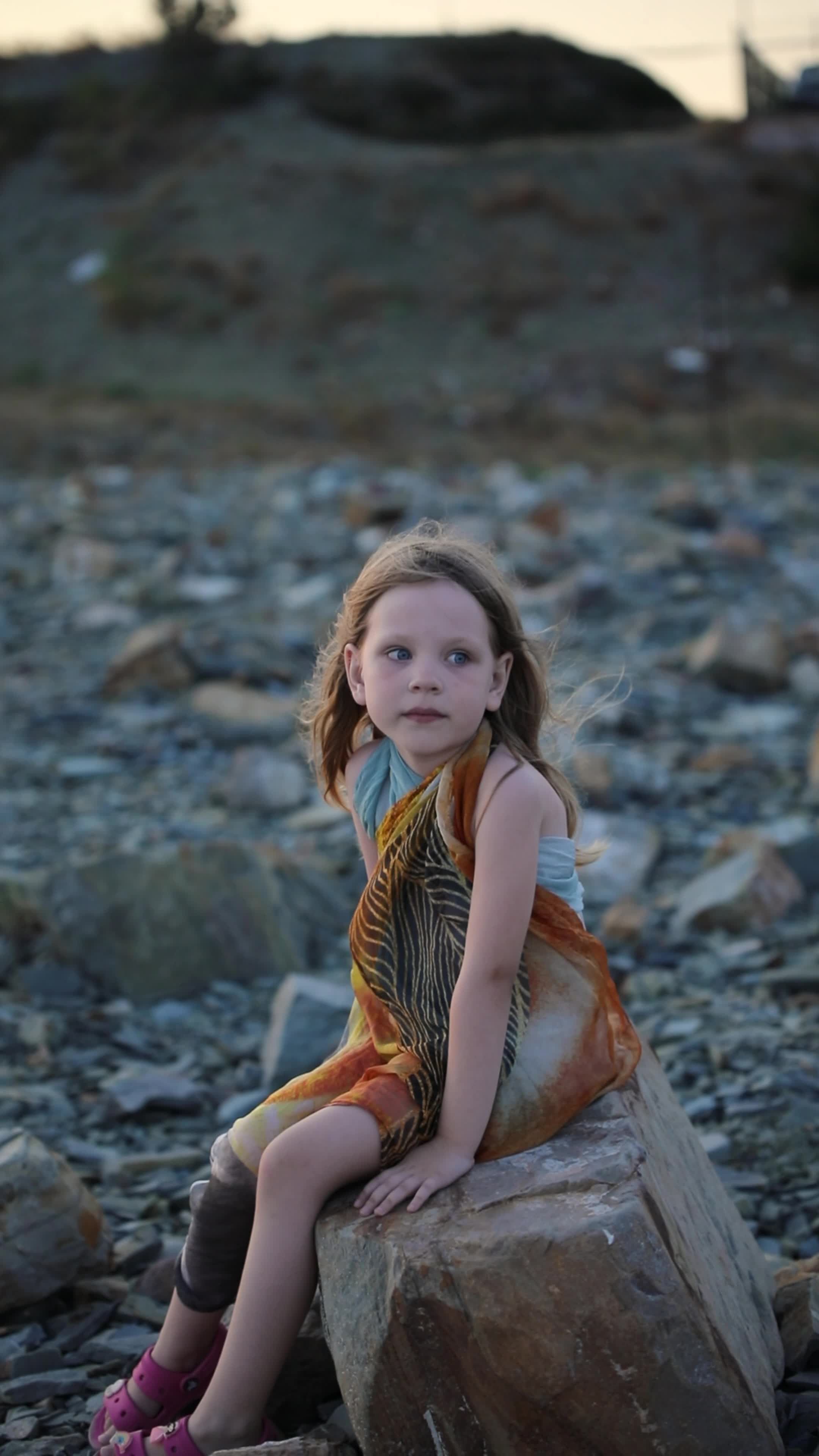 A little girl sitting on a rock in the middle of the ocean Free Stock ...