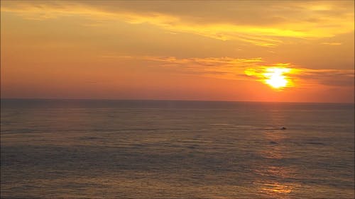 Sun Setting And The Moon Rising In The Horizon Above The Sea