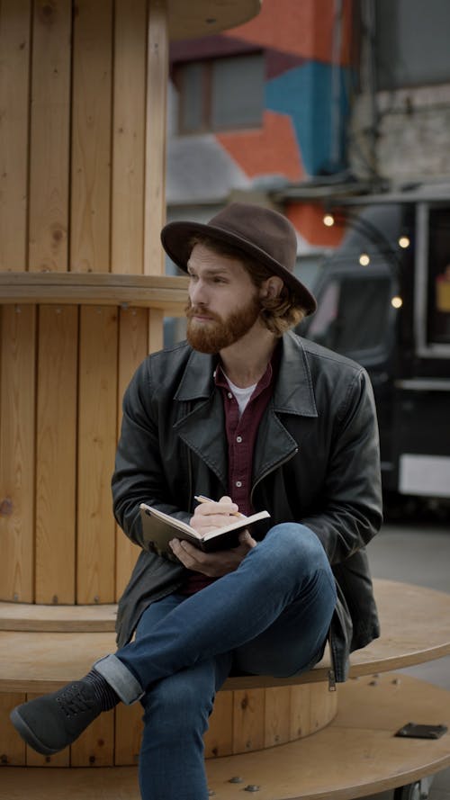 A Man Taking Notes On His Notebook