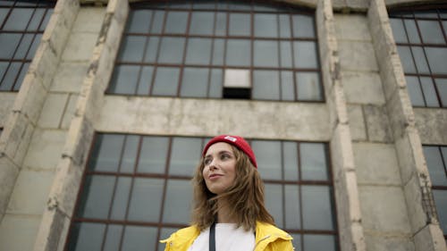 Woman In Red Beanie And Yellow Jacket In Front Of A Building