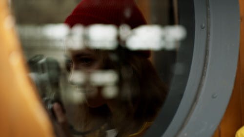 Женщина, делающая фотографию с отражением на стеклянном окне