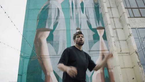 Man Dancing In Front Of A Building With Mural