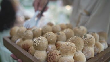 a person holding a tray of bread rolls