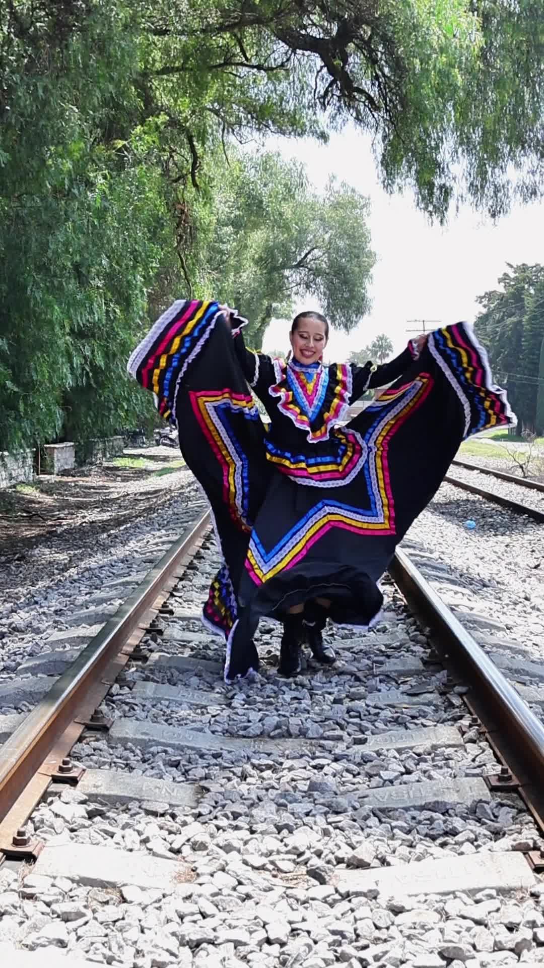 a woman in a mexican dress is walking on railroad tracks 27989031