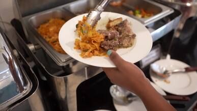 a person holding a plate of food in front of a buffet