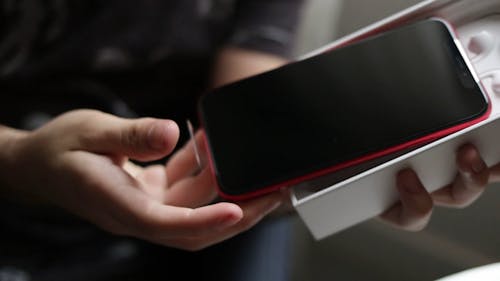 Persona Desempaquetando Un Iphone Rojo
