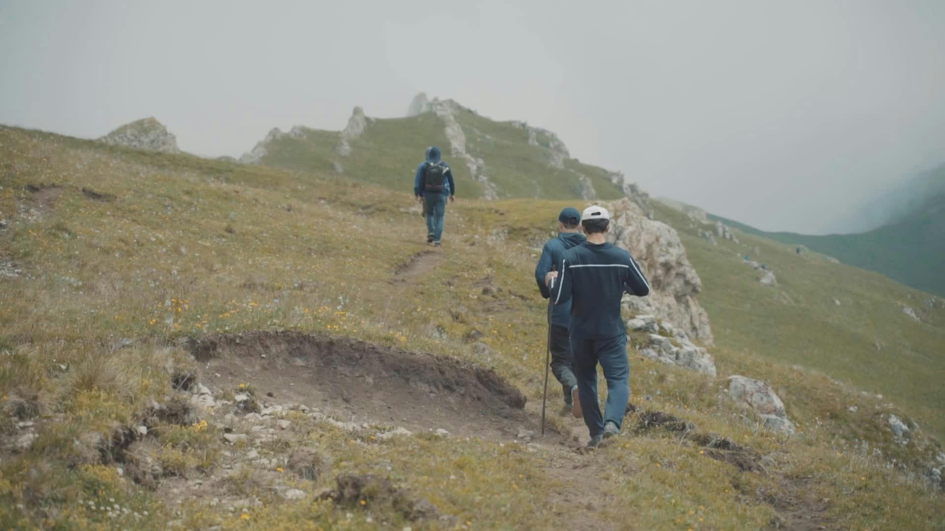 three people walking up a hill on a cloudy day 28267635