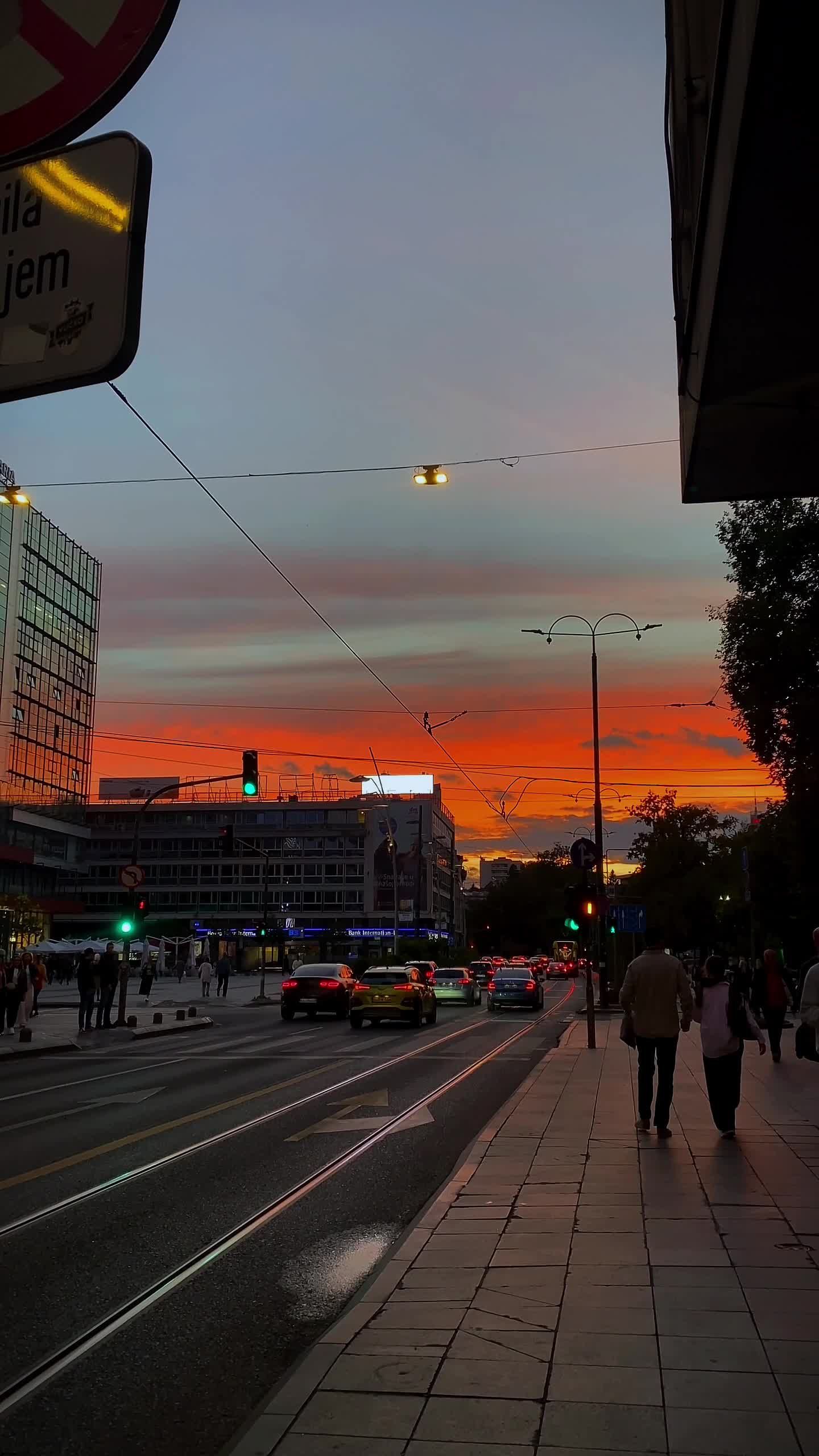a sunset over a city street with cars and pedestrians 28337958