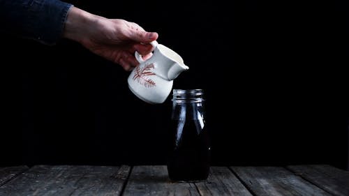 Pouring Milk On A Bottled Black Coffee