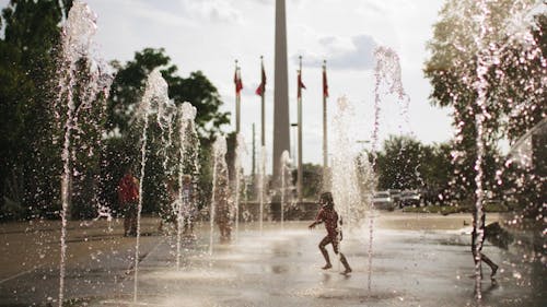 Slow Motion Footage Of Children And Adults Playing In The Water Fountains