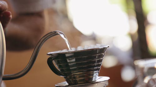 Лить горячей водой переносную чашку с фильтром, наполненную молотым кофе