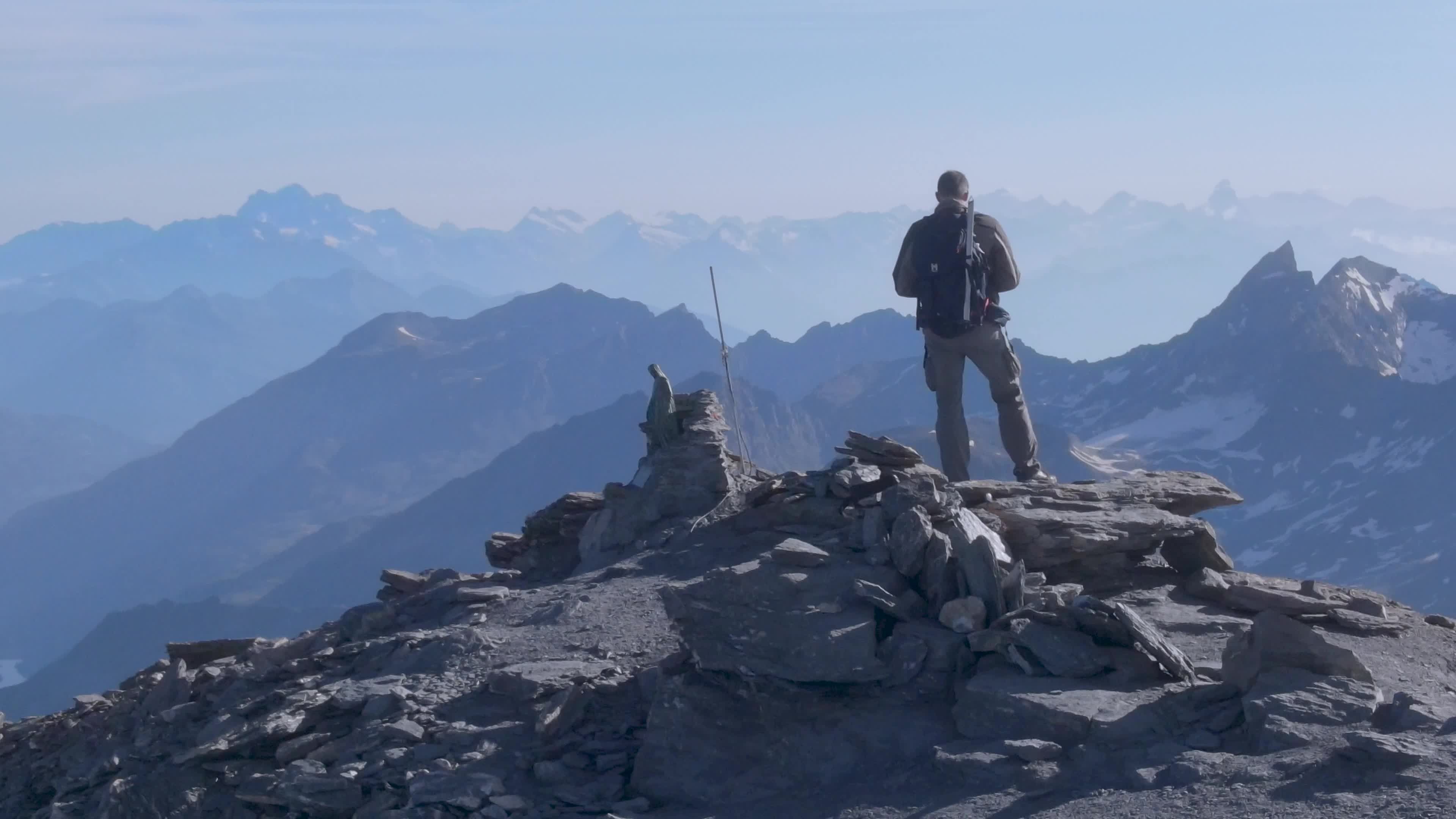 A man standing on top of a mountain with a backpack Free Stock Video ...