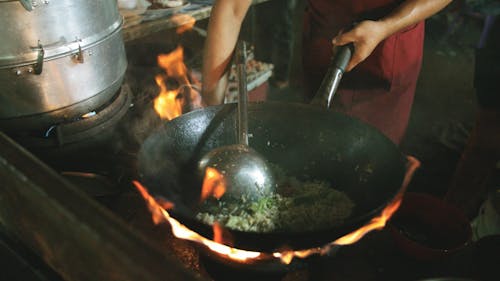 Slow Motion Footage Of A Person Skillfully Mixing Fried Rice In A Wok On A High Fire Stove