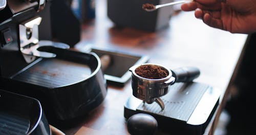 커피 머신의 필터 컵에 원두 커피를 누르는 바텐더