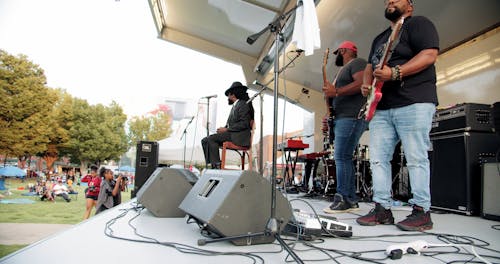A Musician Trio Performs On A Stage In An Outdoors Setting