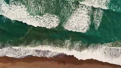 aerial view of ocean waves crashing on beach