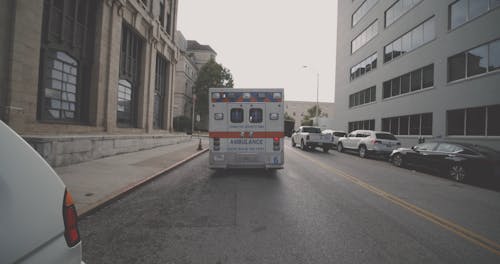 An Ambulance Parked On A Street With Emergency Flashers On