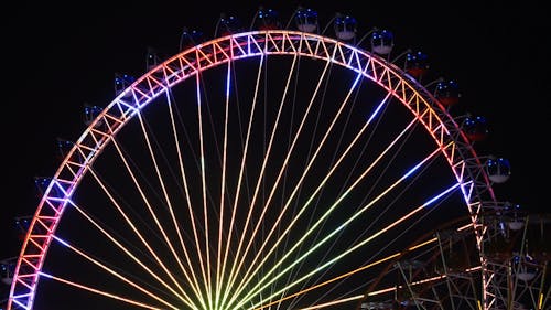 An Observation Wheel With Illuminated Dancing Lights At Night