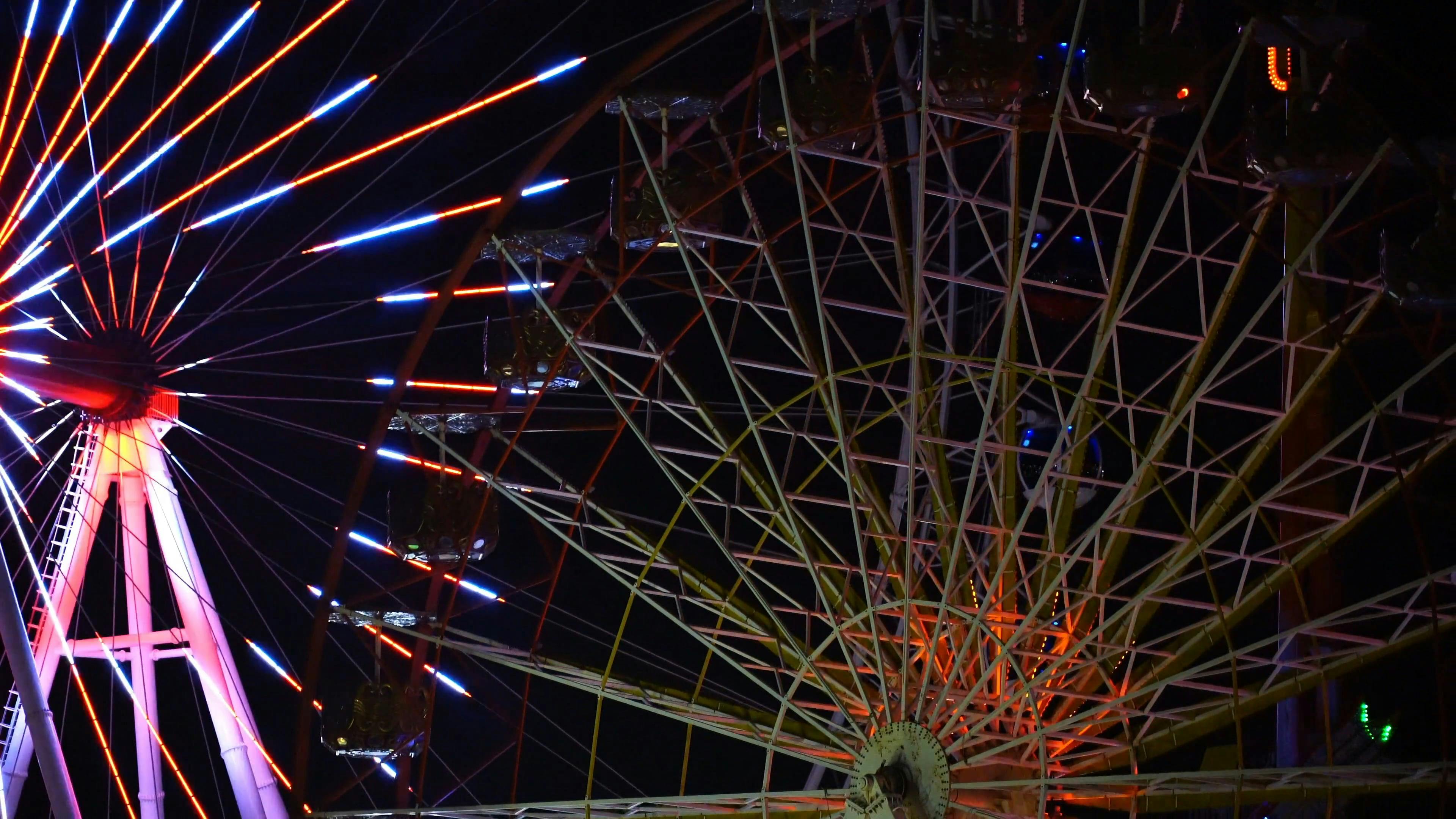 Moving Ferris Wheel Surrounded with Dancing Neon Lights · Free Stock Video
