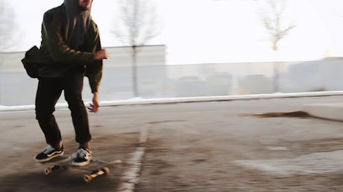 Slow Motion Footage Of A Skateboarder Doing Tricks On the Street Side Under A Bridge