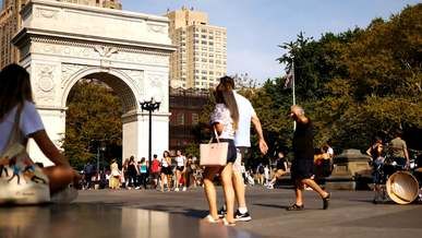 people hanging out and walking around washington square on a breezy day