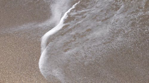 Slow Motion Footage Of Waves Breaking On Sandy Seashore