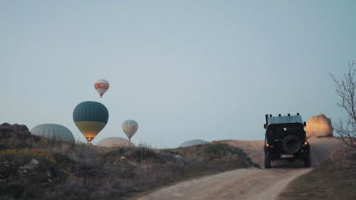 一辆四轮驱动越野车在崎di的土路上行驶，朝着热气球的起飞地点行驶