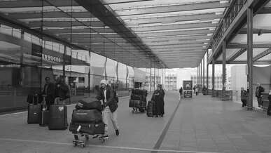 passengers with luggage at airport terminal entrance