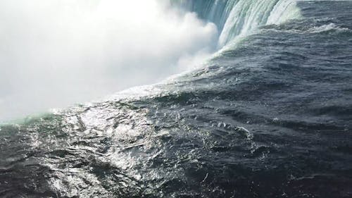 The Downward Force Of The Niagara Falls Produces Mist Of Water