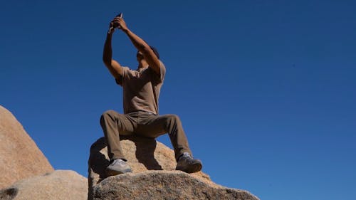 Seorang Pria Berfoto Dengan Duduk Di Atas Batu Besar
