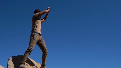 Человек на скале дает инструкции через знаки рукой