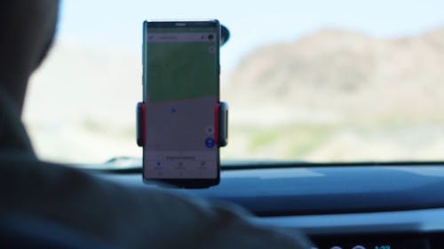 Человек, использующий приложение на своем телефоне для руководства во время вождения