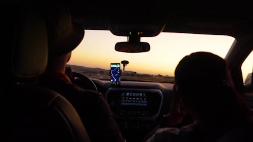 Замедленная съемка двух людей, путешествующих в автомобиле, использующих навигационную помощь со смартфона