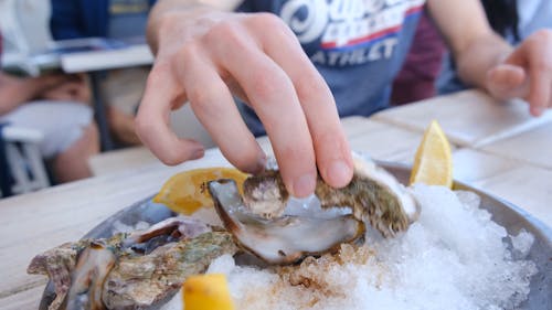 Squeezing A Sliced Lemon On A Fresh Oyster Before Eating It