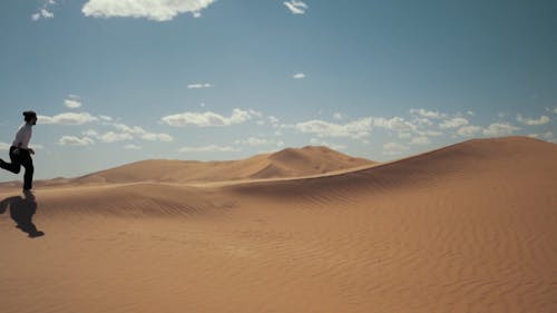 Ein Mann, Der Glücklich In Einem Sandhügel Des Nachtischs Läuft