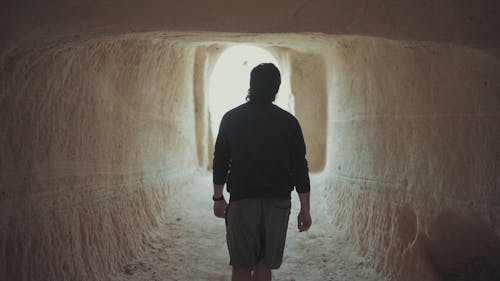一个男人走出一个男人雕刻的古老洞穴的背面
