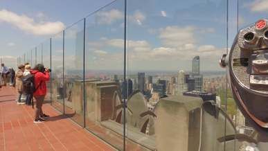 panning footage of people on a view point of a building rooftop looking a the cityscape