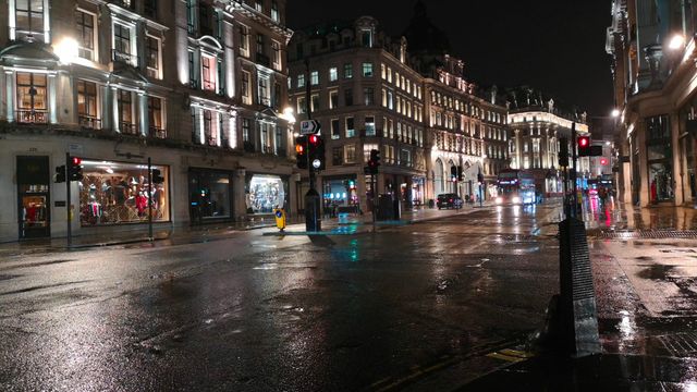 Wet streets and traffic at night in a busy city intersection.