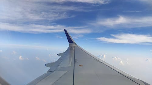 View Of The Blue Sky With White Cloud Formation From The Window Of An Airborne Aircraft