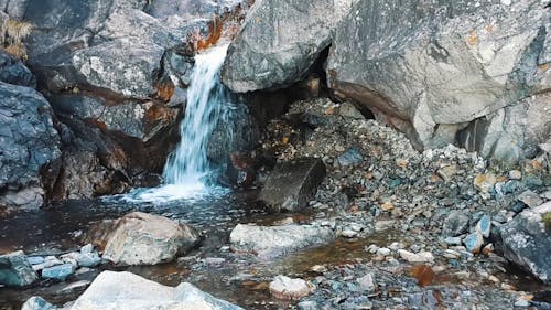 A Natural Spring Of Water Cascading Down The Bed Of Rocks