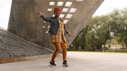 A Woman Dancing Freely Outdoors On A Concrete Pavement