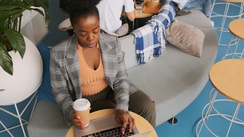 A Woman Working On Her Laptop Inside A Cafe